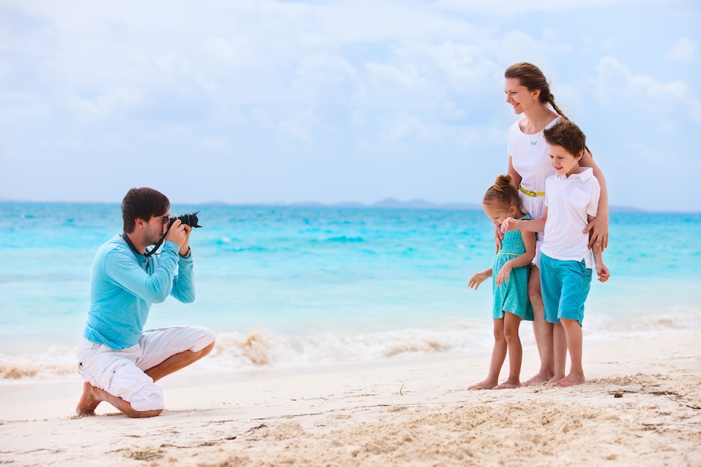 Young man taking photo of woman and kids at the beach