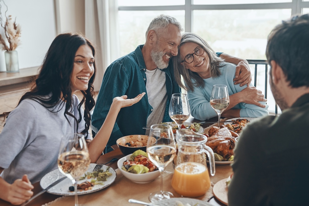 Happy multi-generation family communicating and smiling while having dinner together