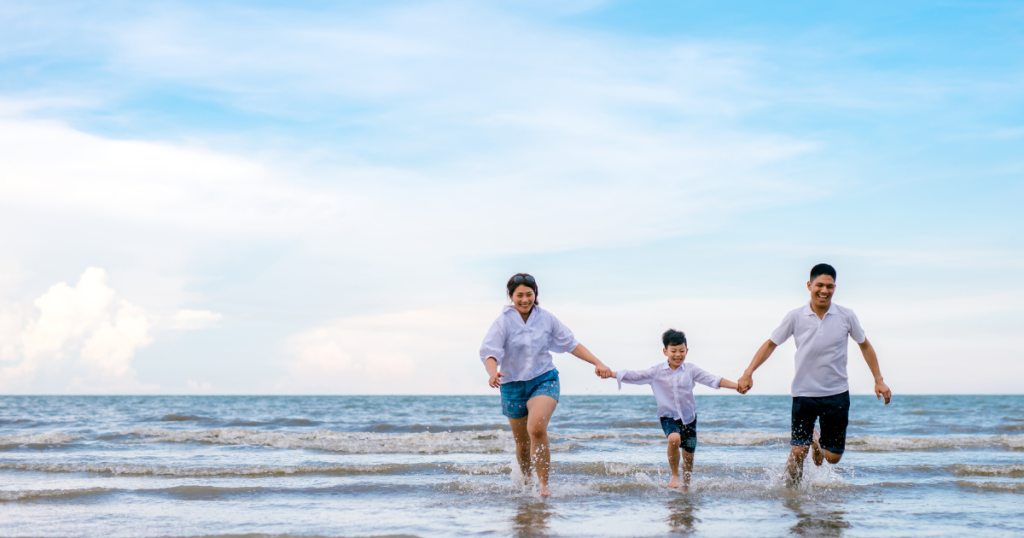 family of three on beach walking in shallow water