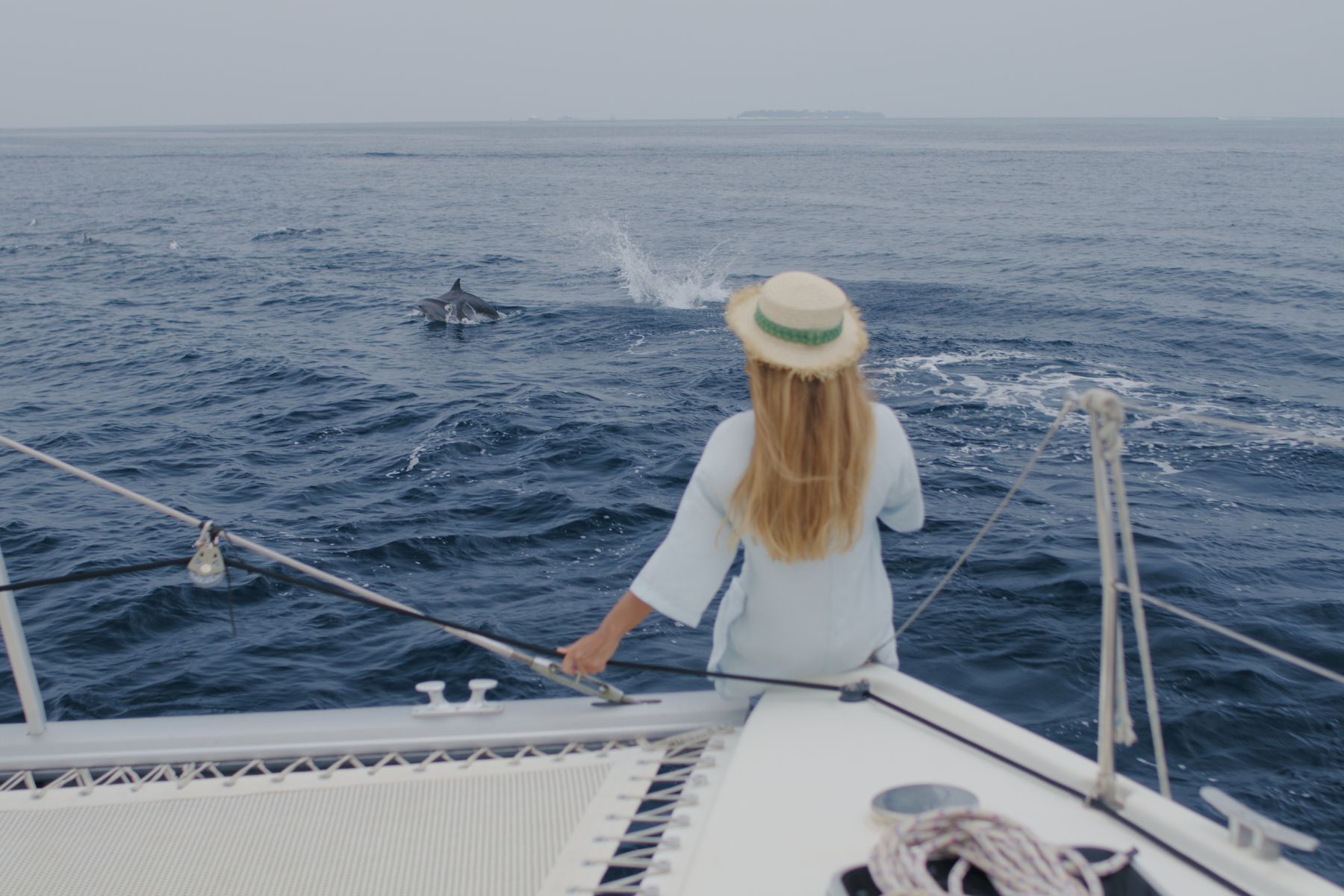 woman standing in boat and watching the dolphins break the water