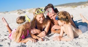 family laughing together in the sand while enjoying an Emerald Coast family vacation