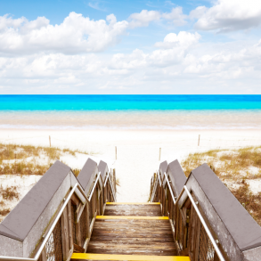 steps walking down to the beautiful Destin shoreline with white sand and blue water