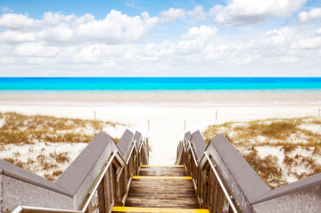 steps walking down to the beautiful Destin shoreline with white sand and blue water