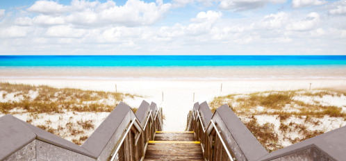 steps walking down to the beautiful Destin shoreline with white sand and blue water