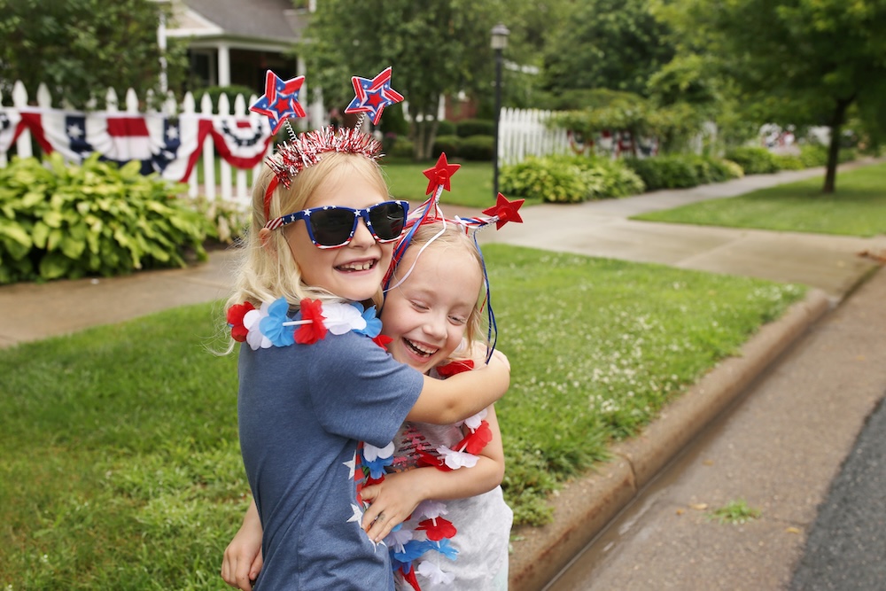 Two happy little girl children are hugging as they celebrate Independence Day.