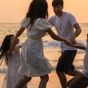 family of four playing on beach at sunset