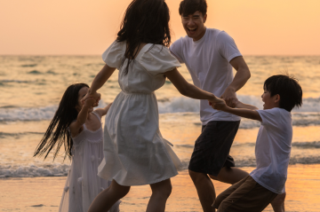family of four playing on beach at sunset