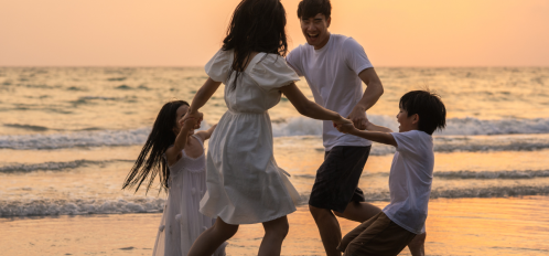 family of four playing on beach at sunset