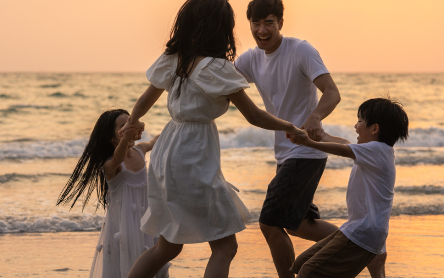 family of four playing on beach at sunset