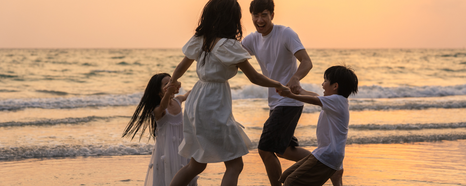 family of four playing on beach at sunset