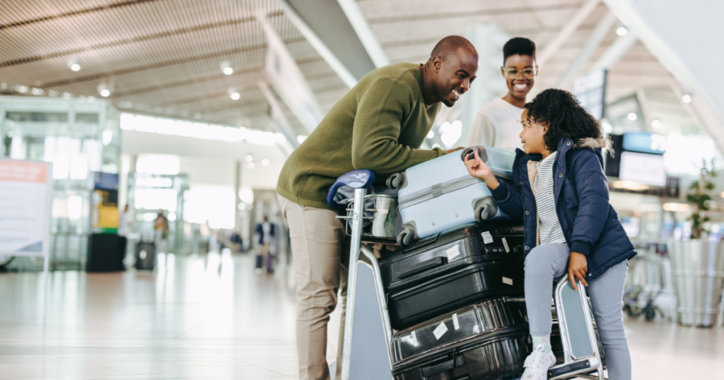 family of three with luggage on a trolley in airport
