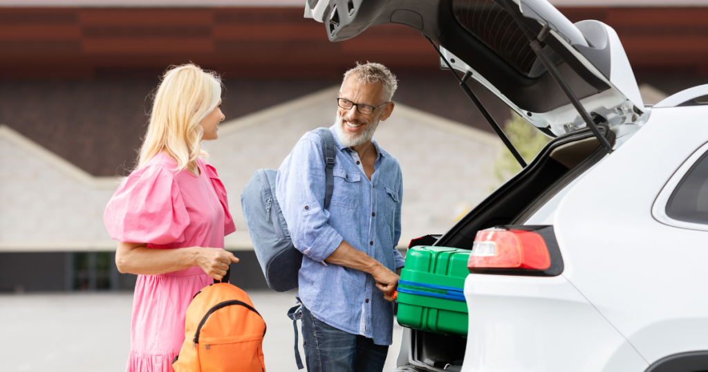 couple putting luggage in the back of a white SUV 