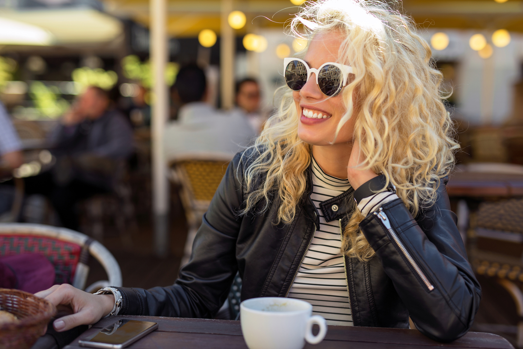 Happy and carefree woman sitting at cafe. Solo female travel.