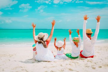 happy family with kids hands up on tropical beach