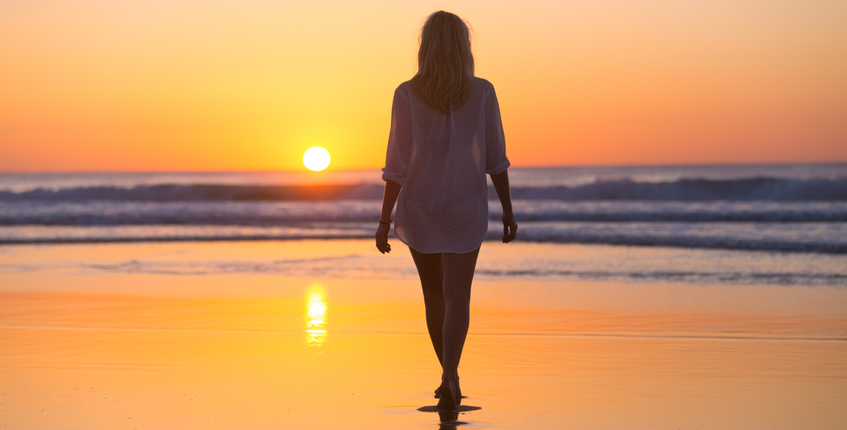 woman walking on the beach at sunset