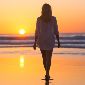 woman walking on the beach at sunset