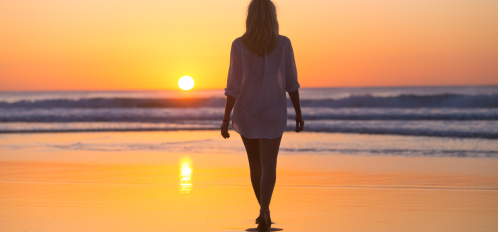 woman walking on the beach at sunset