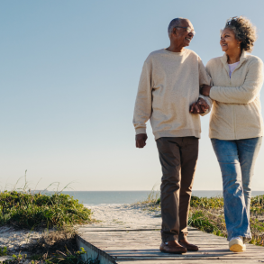 african American couple walking on beach boardwalk with sweater on