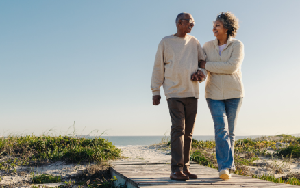 african American couple walking on beach boardwalk with sweater on