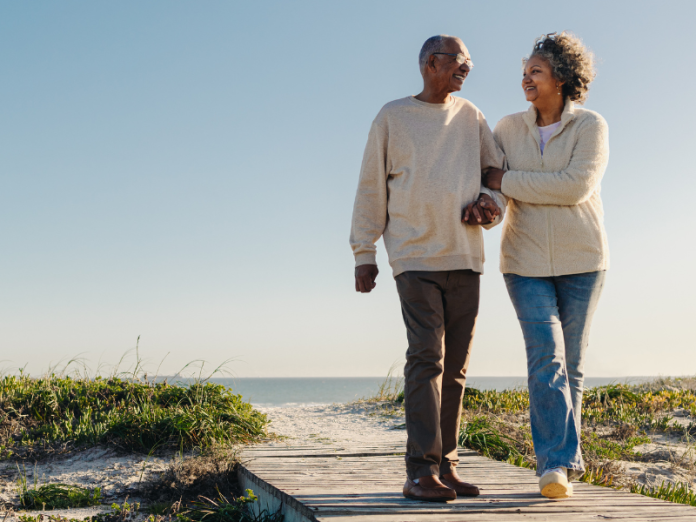 african American couple walking on beach boardwalk with sweater on