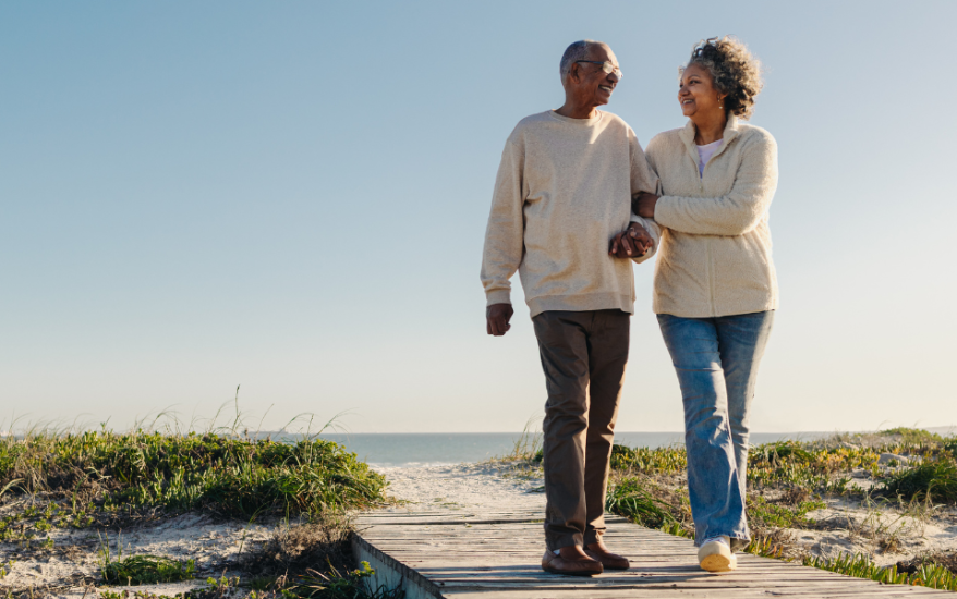 african American couple walking on beach boardwalk with sweater on