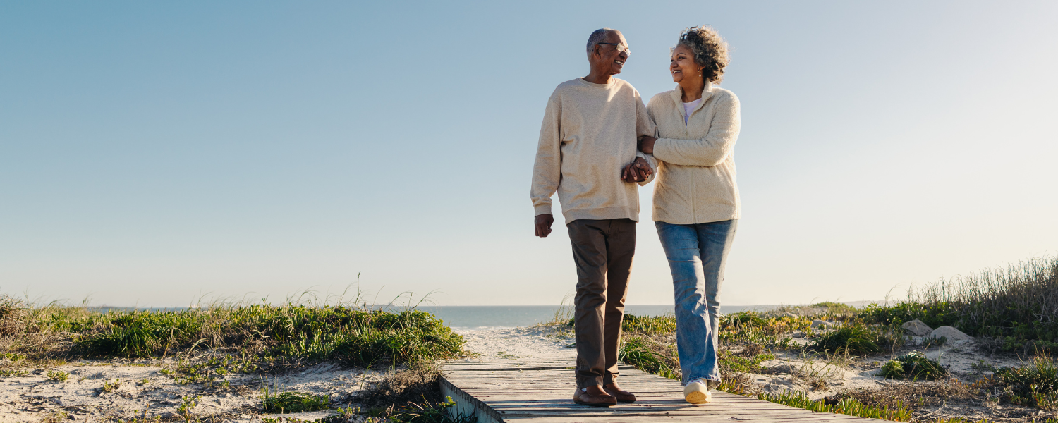 african American couple walking on beach boardwalk with sweater on