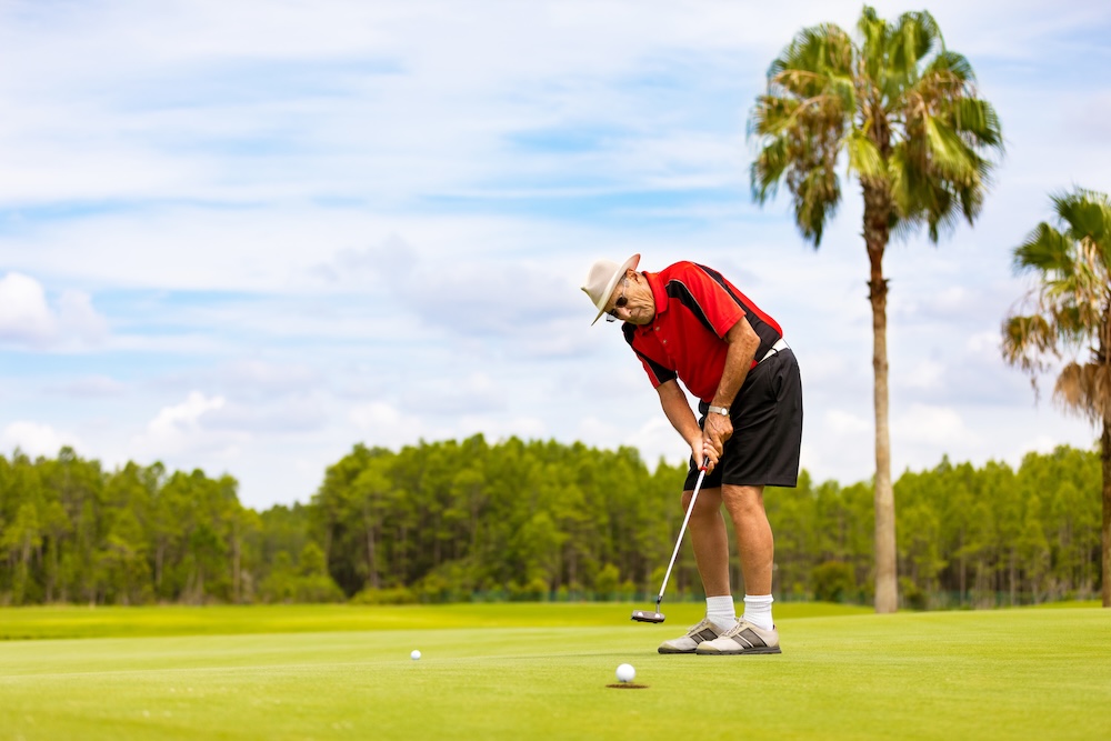 man putting golf ball on green