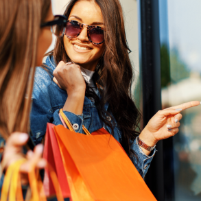 two women with shopping bags looking in store window
