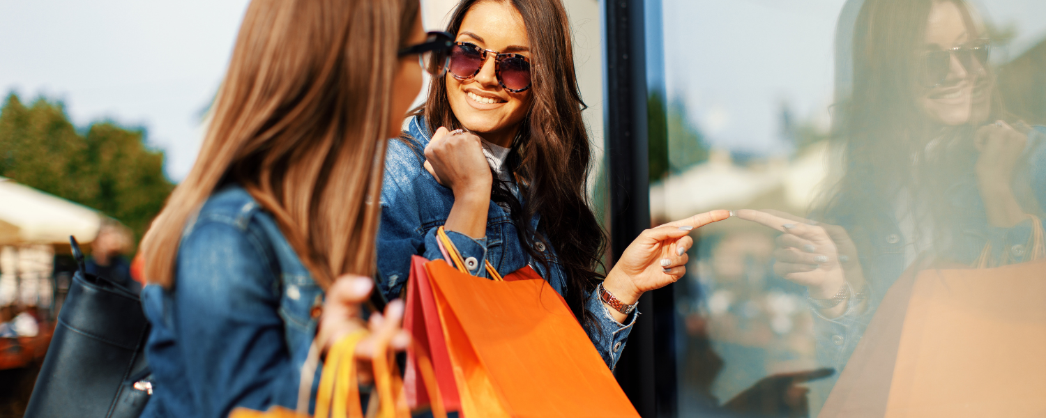 two women with shopping bags looking in store window